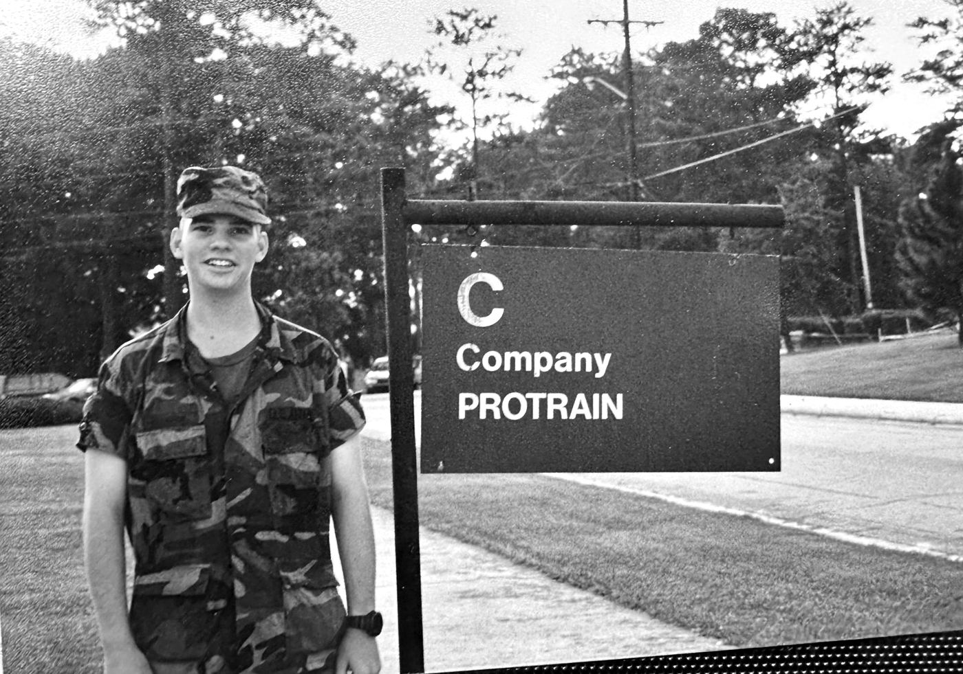 Young Robbie Hardingham in uniform beside the C Company Protrain sign at the Army Quartermaster Center and School